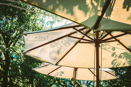 白色太阳光太阳光穿过白色的阳伞 花园家具功能设计装饰品 掌声绿色叶子木头海滩热带椅子遮阳伞森林阴影假期背景