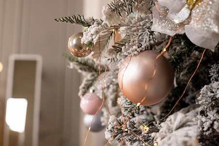 白色精致的圣诞树和圣诞装饰品 球和丝带 花环和灯 粉色珍珠珍珠柔和的颜色 新年贺卡 圣诞节快乐销售卡片玩具营销装饰风格星星季节金背景图片