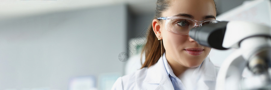 实验室中通过显微镜观察的女科学家化学家背景图片