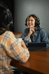 在录音室录制现场播客的同时 在演播室接待采访嘉宾的年轻女士微笑电台图片