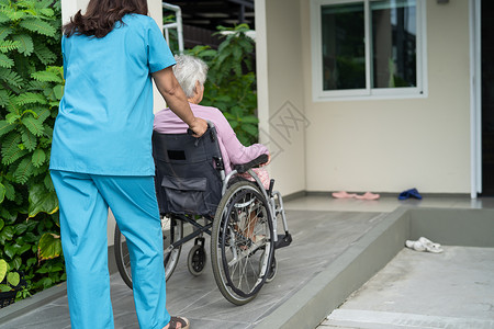 轮椅坡道看护者帮助和照顾坐在轮椅上的护理医院坡道上的亚洲老年或老年老妇人患者 健康强大的医疗理念照顾者公园挑战车轮摩托车退休卫生微笑病人背景