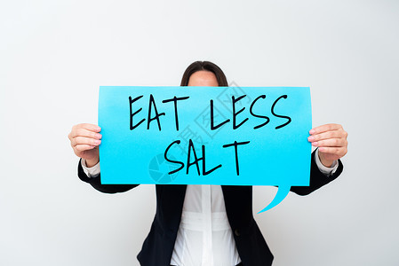 概念标题少吃盐 写在“减少饮食中的钠含量 吃健康的西装女士 拿着笔 象征着成功的团队合作成就”的词背景图片