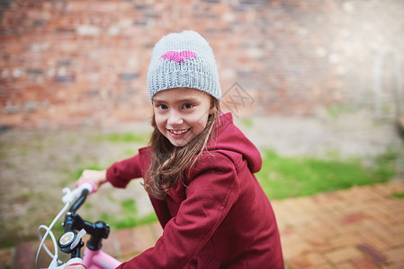 做一个孩子多有趣啊 一个小女孩在外面骑自行车的肖像 (笑声)背景图片