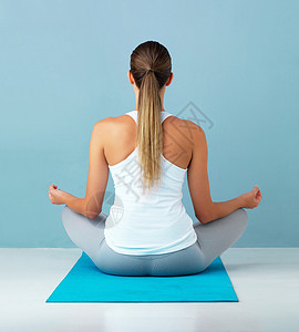 0基础瑜伽班回到基础 一个健康的年轻女子在蓝色背景下冥想的工作室拍摄背景