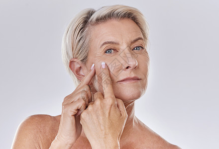 脸皱纹痤疮或粉刺弹出高级女性 同时为健康和透明的皮肤做护肤美容治疗 快乐的老年 成熟或老年女性在脸上捏一个斑点的画像背景