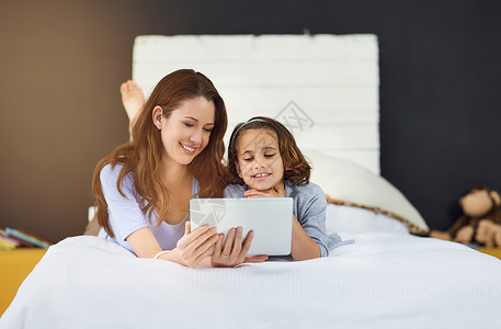 现在的孩子都是关于技术的 一位母亲和她的女儿使用数字平板电脑的全长镜头图片