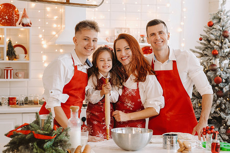 一个幸福的家庭正站在圣诞厨房里 准备做饼干的面粉 为制作饼干准备钱房子女士围裙小姑娘微笑价值观午餐菜肴面团假期背景图片