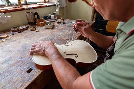 美洲原住民陶器用刀子把小提琴打个洞 雕刻和雕刻螺旋中提琴世界工具制造商风镜工作木制品建设者木材背景