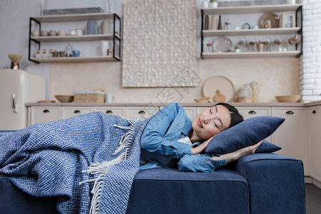 阻塞性睡眠呼吸暂停年轻漂亮的亚洲女人躺在沙发上 躺在毯子下 在家休息和睡觉背景