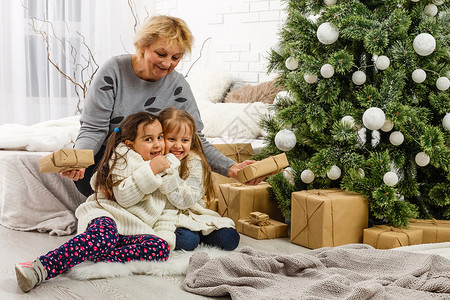 祝妈妈节日快乐圣诞快乐 节日快乐 外婆和孩子们 早上的Xmas 亲爱的肖像家庭房间女士乐趣女孩祖母季节女儿妈妈时间房子背景