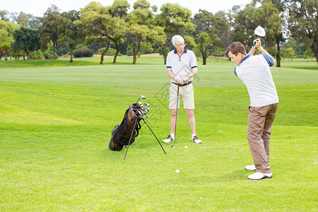 老高尔夫球手他一直在练习挥杆 高尔夫球场的同伴们在玩高尔夫球背景