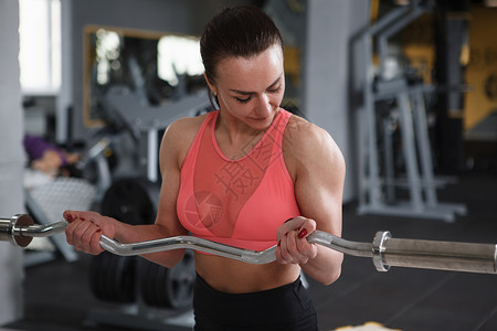 美丽的运动女子在健身房锻炼权重举重身体女士二头肌动机杠铃力量运动员背景图片