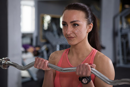 美丽的运动女子在健身房锻炼力量女士举重运动员动机二头肌身体杠铃权重背景图片