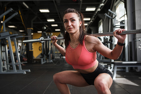 美丽的运动女子在健身房锻炼运动员杠铃下蹲臀部女士功能健美举重动机力量背景图片
