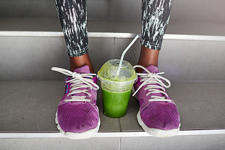 只有两件事你才需要好好锻炼 一杯女运动员双脚之间的果汁 好吗?图片