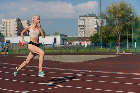 年轻女子在赛道上奔跑竞赛运动速度运动员女性慢跑者身体田径训练运动装图片