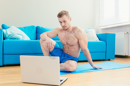 英俊的年轻运动运动员教练训练员在网上用笔记本电脑培训 在家以垫子练习运动垫培训师身体客厅家庭生活肌肉讲师体育锻炼活动运动服背景图片
