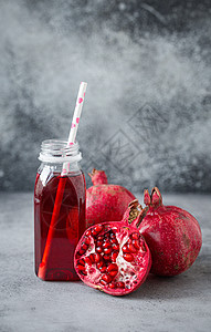 石榴饮料瓶装和水果中的石榴果汁粉色石榴石饮食情调液体红宝石红色饮料浆果桌子背景