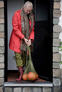 一个穿红色斗篷的中年妇女 连着橙南瓜的红袍打开大门小猫收成国家乡村网兜农民素食主义者女士感恩橙子背景图片