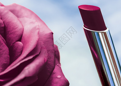 紫色口红和玫瑰花在液体背景上 防水玻璃化妆品和唇膏化妆品产品 用于豪华美容品牌假日设计嘴唇礼物光泽度季节魅力玫瑰假期展示老板香脂背景图片
