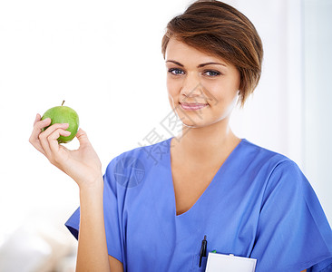 她为病人树立了一个好榜样 一位年轻有魅力的医生拿着苹果洗涤剂画的肖像背景图片