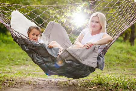 母亲和女儿一起睡在花园哈默克女孩假期孩子休息海滩吊床亲热女性孩子们成人背景图片