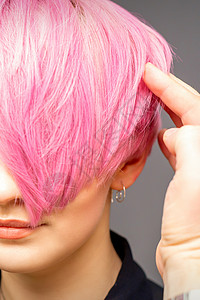 粉色发廊元用手梳发的发型师正在检查 并修补短粉红色的发型 在一个发廊里 年轻白种女人女性客户造型师女孩理发工作治疗化妆品服务敷料背景