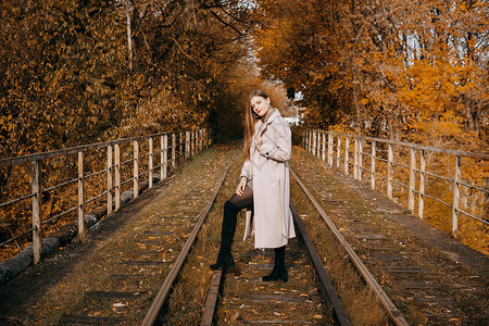 秋天火车美丽的长发美女走在秋天的街道上 铁路 秋天 穿大衣的女人国家女孩时尚木头小路季节叶子火车女性森林背景