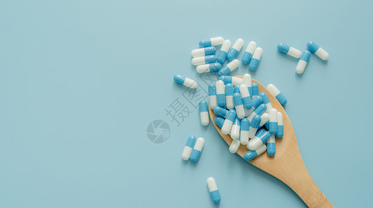 抗菌抗病毒在木匙子和蓝色背景的青白色抗生素胶囊药片 抗生素耐药性 处方类药物 医疗 医药保健 抗菌药物 世界药剂师日背景