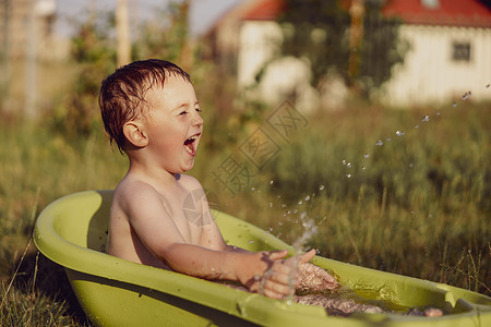 泼水的小男孩可爱的小男孩在花园里的户外浴缸里洗澡 快乐的孩子在泼水 玩水 玩得很开心 夏季和娱乐 在炎热的夏季保持凉爽 在后院玩水假期花园微背景