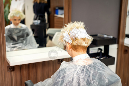 坐在美发沙龙的年轻白人金发女子用染发剂给白发上色 特写理发店服务女士护理客户染色发型发型师女性理发师背景图片