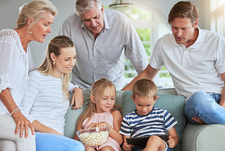 流媒体 媒体和家人一起在客厅观看互联网移动应用程序上的平板电脑电影娱乐 幸福的家庭成员喜欢在家庭休息室观看有关技术的在线团聚电影背景图片
