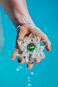拿着易碎的莲花的妇女 清澈的水珠从水晶中滴落 宗教 昆达里尼 冥想 脉轮 精神内心世界的概念椭圆形水晶花美丽矿物女性女士游泳池玻背景图片
