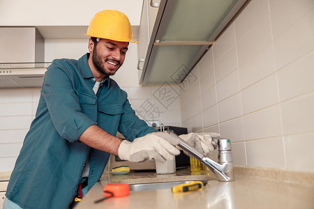微笑的男性水管工在客户厨房修理水槽水龙头 优质的水暖公司服务浴室高清图片素材