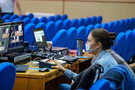 戴着防护面罩的年轻女性视频编辑在会议 研讨会上工作 使用笔记本电脑编辑视频流式传输到互联网 社交媒体背景