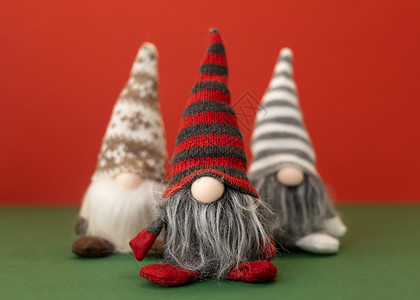 红色帽子红色背景的3个圣诞小矮黑猩猩魔法胡须团体朋友们玩具新年季节帽子假期情绪背景