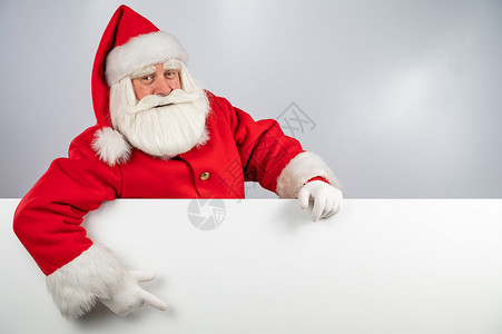 圣诞老人从白色背景中探出头来 用手指指着一个空旷的地方 圣诞节快乐手套海报手势帽子祖父戏服横幅传统男人卡片背景图片