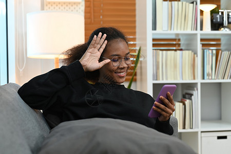 坐在舒适的沙发上 在社交网络上聊天 在智能手机上进行视频电话等节目中 让年轻少女感到愉快;背景图片