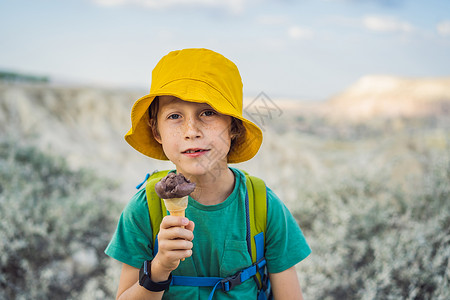 男孩卖冰淇淋在土耳其卡帕多西亚Goreme附近与岩石构造和仙子洞穴一起探索山谷时 男孩旅游男孩吃土式冰淇淋火鸡游客假期旅游家庭食物锥体甜点商背景