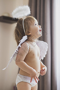婴儿丘比特有翅膀和光环的可爱女婴 热情地仰望着背景