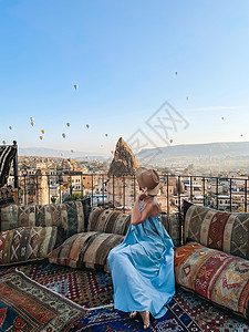蓝色老鼠气球穿着衣服在屋顶上衣着的年轻女子 在土耳其的景色令人惊叹女士飞机女孩旅行蓝色天空旅游时间冒险裙子背景