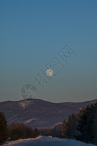 冬天月亮月亮在山上和路上飘扬背景