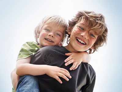 快乐的小男孩背着他的弟弟骑车 一个快乐的小男孩给他弟弟搭便车的特写肖像图片