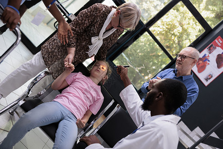 病人晕倒在路上非洲美籍医生在体检访问期间 在医院接待处帮助女孩坐在椅子上晕倒后帮助女童背景