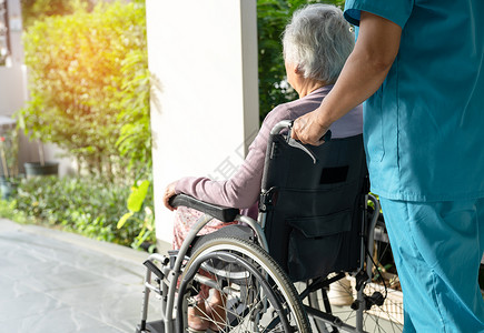 沃基根看护者帮助和照顾坐在轮椅上的护理医院坡道上的亚洲老年或老年老妇人患者 健康强大的医疗理念女士车轮卫生摩托车诊所公园保健护士街道发背景