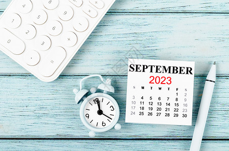 9月月历2023年9月的月历年和有蓝木本底计算器的闹钟背景