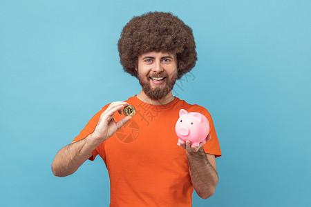 自信小猪表情男人拿着小猪银行和金比特币 看着摄影机带着快乐的表情背景