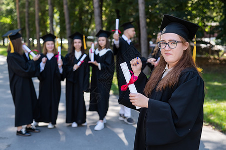 技能升级证书一名戴眼镜和毕业礼服的黑人年轻女子在同学背景下被画成肖像 一群研究生户外活动 见ECN 4Sub 220016 附件中学丝带朋友背景