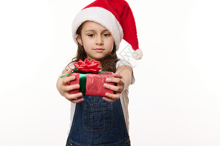 中东小女孩白色背景的肖像可爱的小女孩戴着圣诞老人的帽子 拿着可爱的礼物 圣诞节前夕 新年 寒假背景
