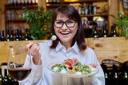 中年快乐女人在餐厅吃沙拉 面贴脸的喜悦背景图片